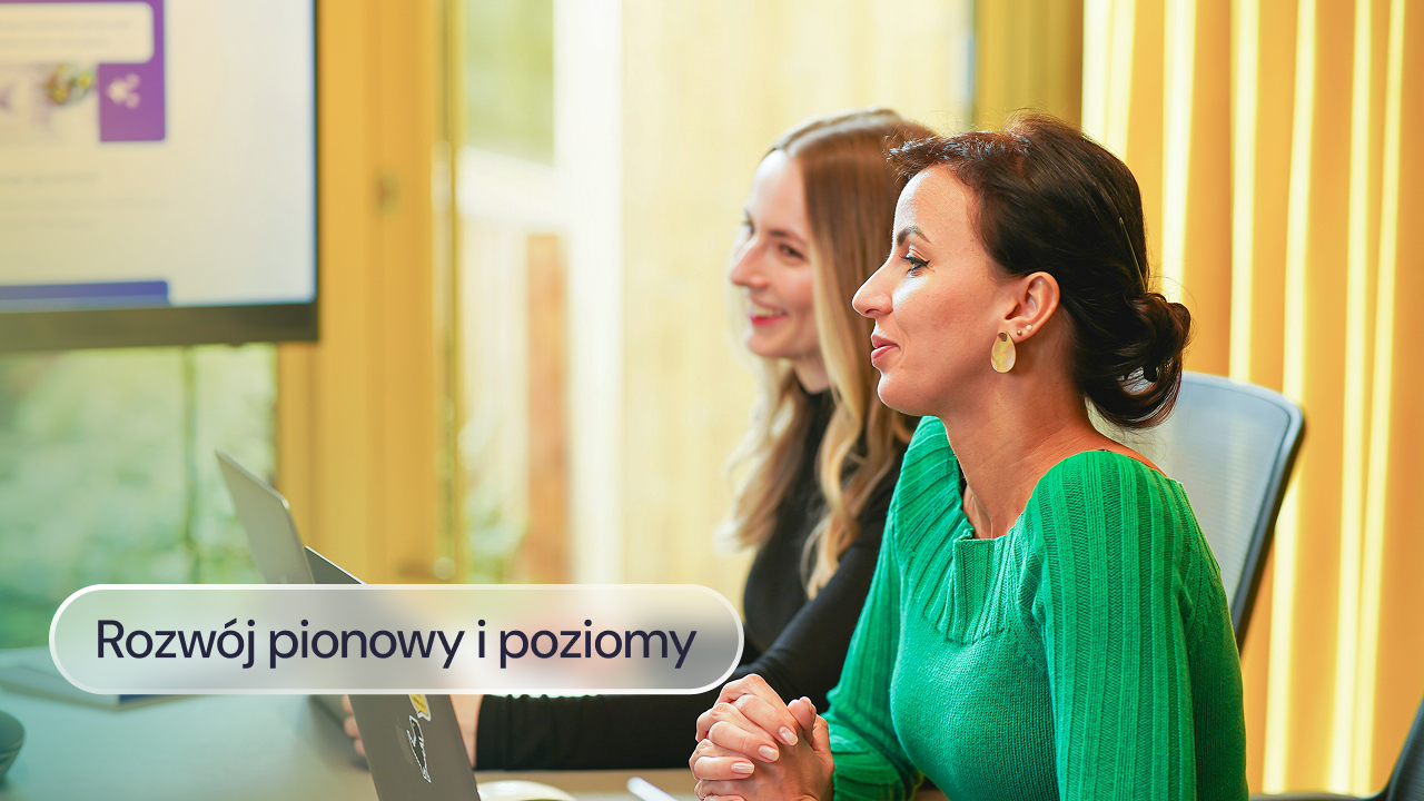Dwie kobiety przy biurku omawiają dokumenty na komputerze.