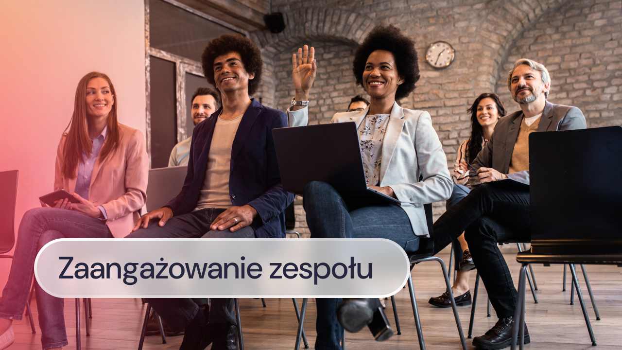 Zespół uczestniczy w spotkaniu i jedna z kobiet podnosi rękę.